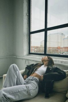 a woman laying on top of a couch next to a window