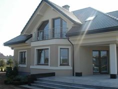 a two story house with large windows and stairs leading up to the front door area