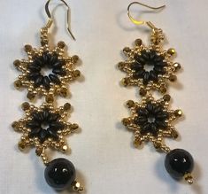 These stunning beauties are part of the Nadine Glassman Collection - are hand-woven with black Czech SuperDuo two hole 2.5x5mm seed beads, gold 11/0 seed beads, gold glass 3mm round, and one 10mm black glass round bead, strung on 8lb FireLine crystal thread and are hung on gold-plated fishhook earrings. The length are 3-inches and approximately 1-inch wide. Retail $17.95. Adjustable Black Jewelry With Bead Caps, Traditional Black Jewelry With Bead Caps, Black Beaded Earrings With Round Beads As Gift, Black Beaded Round Earrings, Adjustable Gold Beaded Earrings With Black Beads, Elegant Black Beaded Earrings With Gold Beads, Black Beaded Drop Earrings With Gold Beads, Black And Gold Beaded Drop Earrings, Gift Black Beaded Earrings With Gold Beads