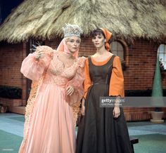 two women in dresses standing next to each other on the set of a television show