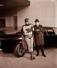 two men in costumes standing next to an old car