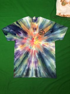 a tie - dyed shirt with the letter g on it is laying on a green surface