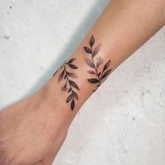 a woman's foot with a black and white tattoo design on it, featuring leaves