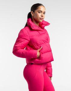 a woman in a bright pink jacket and leggings is posing for the camera