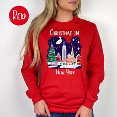 Christmas in New York Long-Sleeve T-Shirt, New York Christmas Vacation Gift, Christmas at Rockefeller Center, New York City Long Sleeved Tee. Orders are processed within 24 hours and shipped out within 2 to 5 business days.  What you receive: Gildan Mid-Weight Long-Sleeved Crewneck T-Shirt Color Choices: White Red Forest Green Sizes: Unisex adult sizing - these long-sleeved tees tend to run small - if you want a relaxed fit go one size larger. Shirt Detail: A bit more formal than a standard-issu Red Long Sleeve Christmas T-shirt, Festive Long Sleeve Holiday T-shirt, Festive Long Sleeve T-shirt For Holiday, Festive Long Sleeve Tops For New Year, Long Sleeve Graphic T-shirt For Holidays, Long Sleeve Graphic Print T-shirt For Holiday, Graphic Print Tops For New Year Holiday, Holiday Long Sleeve T-shirt With Letter Print, Festive Red Long Sleeve T-shirt