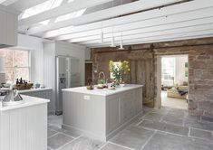 a kitchen with an island, sink and stove in it's center area next to a brick wall