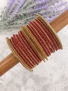 Rumana bangle set. Comes in multiple colors. All comes with 12 colored metal bangles with gold dots. 4 antique size Kada. 4 rhinestone bangles and 4 antique churi. Maroon Bangles Set, Red Bangles Set Bridal, Red Bohemian Bangle For Festive Occasions, Red Bangle Bracelets With Zari Work, Festive Stackable Beaded Bangle Bracelets, Bollywood Style Beaded Gold Bracelets, Red Bohemian Bangle For Festive Season, Red Zari Work Bangle Bracelets, Bollywood Style Gold Beaded Bracelets