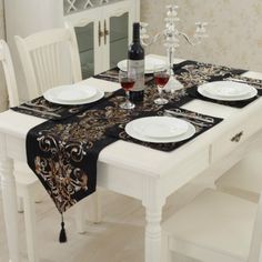 the table is set with white plates and black napkins, wine glasses on it