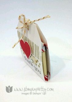 an open gift bag tied with twine and paper hearts on it's side