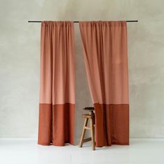 an orange and brown curtain hanging on a wall next to a wooden stool in front of it