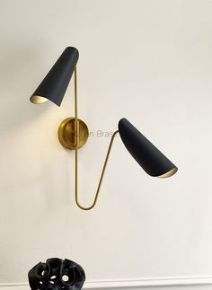 two black lamps mounted on the wall next to each other in a room with white walls