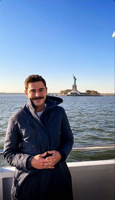 a man standing in front of the statue of liberty with his hands on his hips