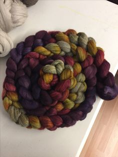 several skeins of yarn sitting on top of a white table next to balls of yarn