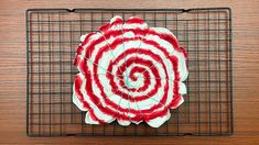 a red and white striped flower sitting on top of a metal wire cooling grate