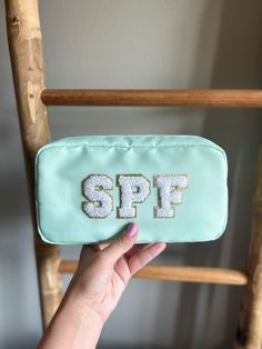 a person holding up a small bag with the word spf on it in front of a chair