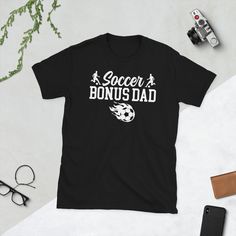 a t - shirt that says soccer bunus dad on it next to some glasses