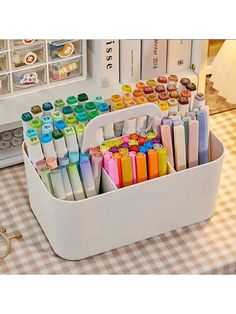 a white container filled with lots of different colored pens next to a pair of glasses