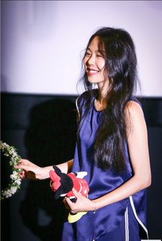 a woman in a blue dress holding flowers