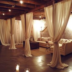 a living room filled with lots of white drapes and candles in front of it