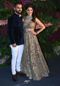 two people standing next to each other in front of flowers and greenery at an event