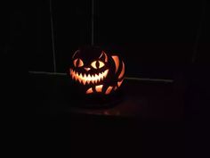 a carved pumpkin sitting on top of a table in the dark with its mouth open