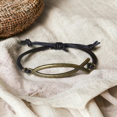 This unique Jesus Fish Bracelet features a minimalist yet striking design, crafted to showcase your faith and style. The bracelet highlights a vintage-inspired brass Ichthys symbol, a timeless emblem of Christianity, securely attached to a dark braided leather band. Ideal for both men and women, this bracelet offers an adjustable fit for any wrist size, making it a versatile piece for daily wear or special occasions. Its combination of genuine leather and brass adds a touch of elegance and durability, ensuring it remains a cherished accessory for years to come. Details: Material: Brass Ichthys Symbol & Genuine Braided Leather Adjustable Knot Design for a Comfortable Fit Bracelet Length: Adjustable to accommodate various wrist sizes Color: Dark Brown Leather & Antique Brass Perfect Gift for Fish Bracelet, Fishing Bracelet, Leather And Brass, Christmas Gift For Him, Adjustable Knot, Securely Attached, Fitness Bracelet, Braided Leather Bracelet, Christian Jewelry