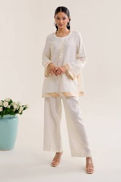 Ivory top with sequin embroidery and contrasting border. Paired with coordinating flared pant. - Aza Fashions Elegant White Pant Set With Resham Embroidery, Elegant Cotton Sharara With Embroidered Border, Beige Long Sleeve Sets With Embroidered Border, Chic White Festive Sets, Chic Festive White Sets, Elegant White Embroidered Pant Set, Festive White Pant Set With Floral Embroidery, Cream Embroidered Palazzo Set For Eid, White Cotton Sets With Embroidered Hem