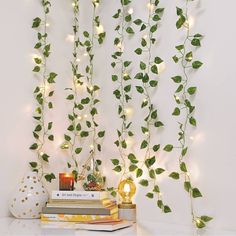 the wall is decorated with green leaves and white lights, along with books on a table