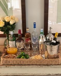 a wooden tray topped with lots of bottles and glasses next to flowers on top of a table