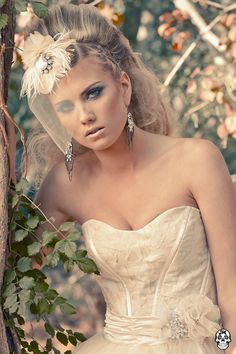 a woman in a wedding dress leaning against a tree