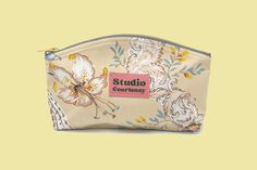 a small pouch with a floral design on the front and side, sitting against a yellow background