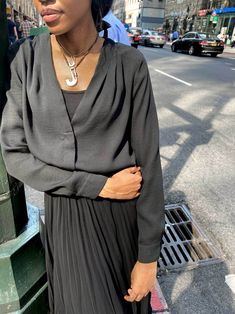 a woman standing next to a pole in the street with her hands on her hips