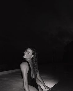 a black and white photo of a woman in a bathing suit sitting on the ground