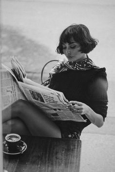 a woman sitting on a bench reading a newspaper