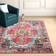 a blue chair sitting on top of a wooden floor next to a red and green rug