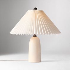 a white table lamp with a beige shade on it