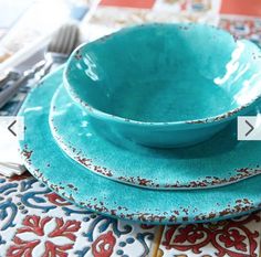 a stack of blue dishes sitting on top of a table next to utensils