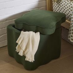 a green foot stool with a blanket on it