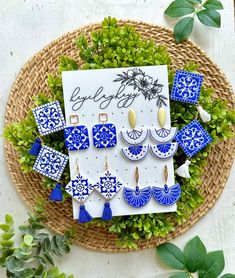 blue and white earrings sitting on top of a basket next to green plants with greeting card