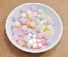 a bowl filled with marshmallows on top of a wooden table