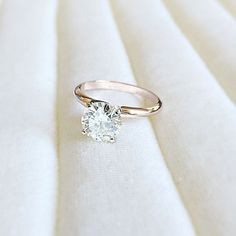 a diamond ring sitting on top of a white cloth covered tablecloth with a gold band