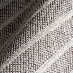 closeup of white and beige knitted fabric with diagonal stripes on it, as well as the background