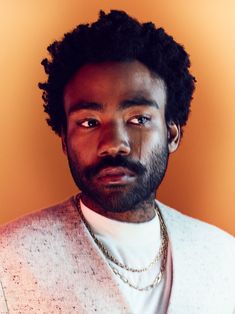 a man wearing a white sweater with a beard and necklace on his neck is looking at the camera