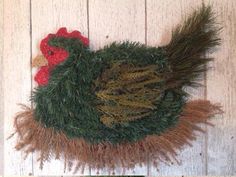 a close up of a fake chicken on a wooden wall with grass and feathers around it