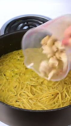 someone is pouring something into a pot of noodles