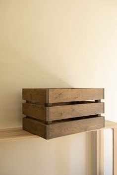 a wooden box sitting on top of a shelf next to a white wall in an empty room