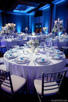 the tables are set with white linens and centerpieces for an elegant event