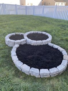 two circular stone planters sitting in the middle of a yard with grass around them