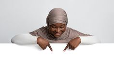 a woman wearing a headscarf leaning over a white board with her hands on the edge