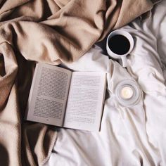 an open book and cup of coffee on a bed